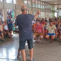 A man addressing a seated group inside a hall