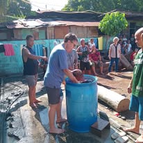 Participants gathered beside a blue water barrel