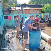 Ministry gathering around a blue water barrel outdoors